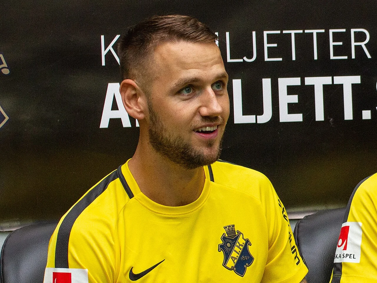 Alexander Milošević i AIK:s gula träningströja på avbytarbänken 2018