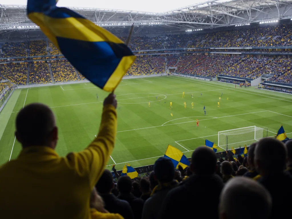 Fotbollsstadion med blå och gula fans på läktaren under ett klassikermöte mellan IFK Göteborg och AIK