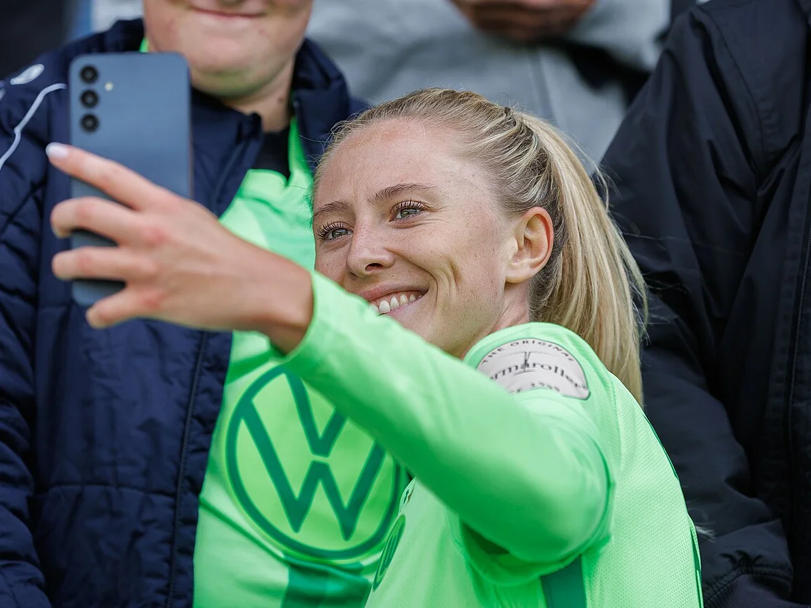 Rebecka Blomqvist i VfL Wolfsburgs gröna tröja tar en selfie med en supporter efter en Bundesliga-match 2024