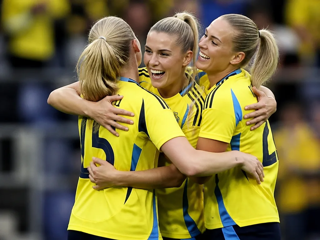 Svenska damlandslaget i fotboll firar på planen i gula och blå tröjor
